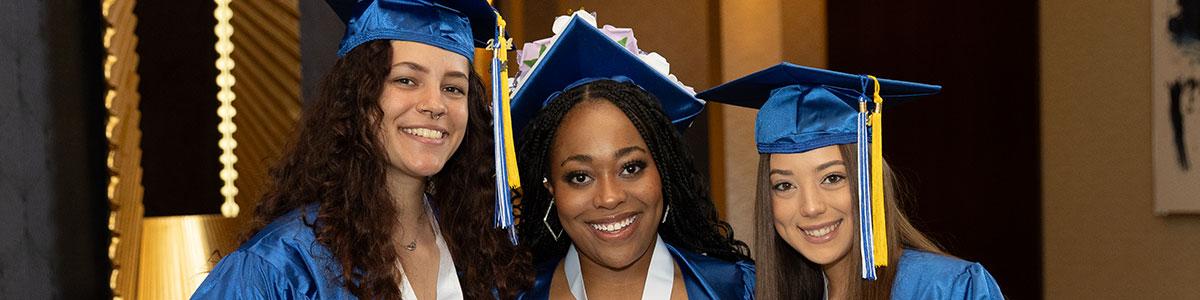 Three AACC graduates smiling at Commencement ceremony